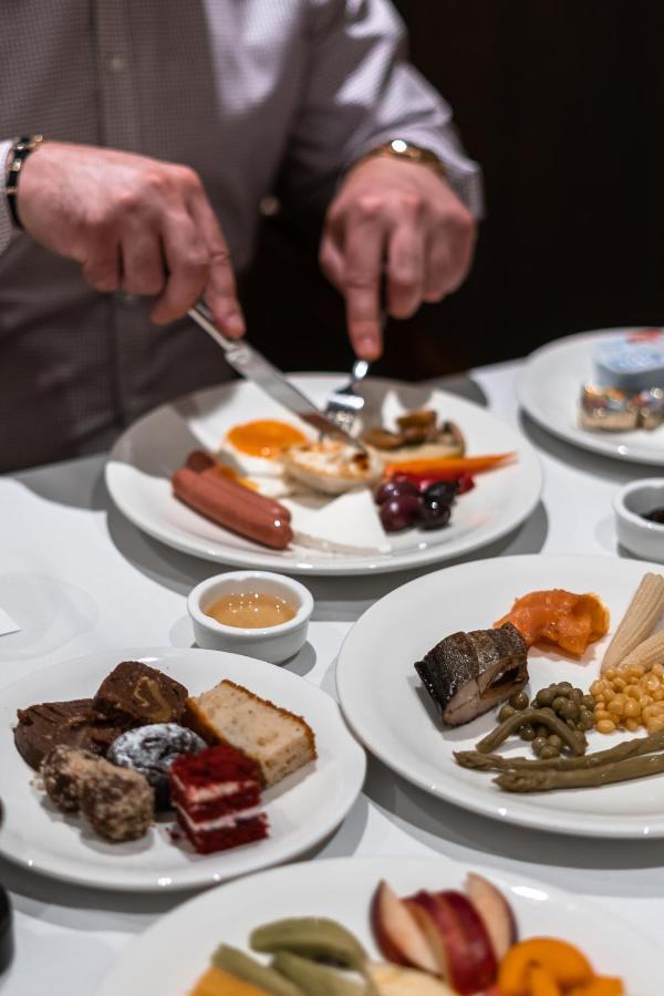 Hotel Manami Pristina Esterno foto A person using a knife and fork to eat a meal